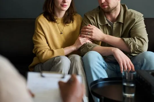 Profissional conversando com um casal durante uma sessão de orientação e formação